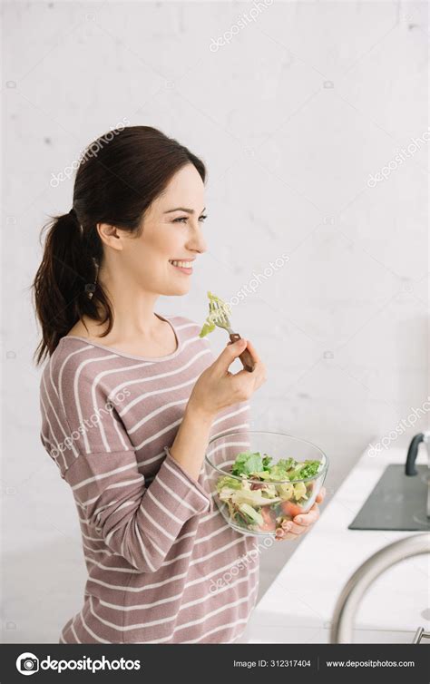 Attractive Cheerful Woman Looking Away While Eating Vegetable Salad