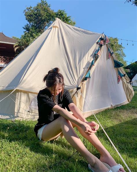 A Woman Sitting On The Ground Next To A Tent