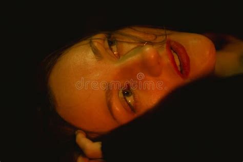 Woman With Red Lipstick Looking Away From The Camera In A Dark Room