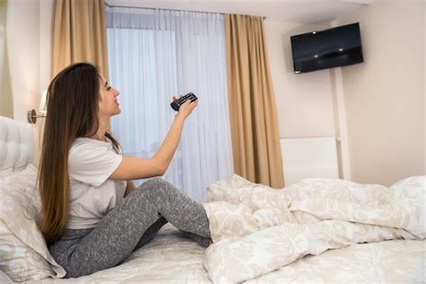 Mulher assistindo tv deitada na cama pela manhã Foto Premium