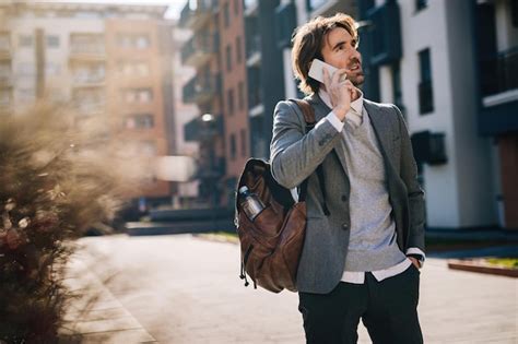 Jovem empresário falando no celular em pé na rua Foto Grátis