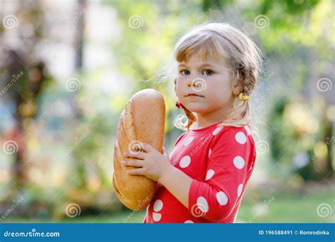 Little Toddler Girl Holding Big Loaf Of Bread Funny Happy Child Biting