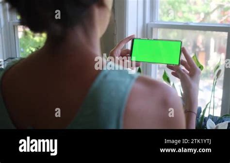 Woman With Smart Phone With Green Screen Chroma Key At Home Looking At