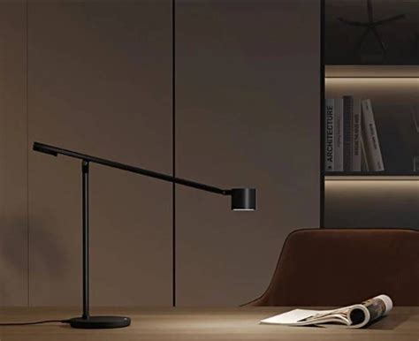 a desk lamp sitting on top of a wooden table next to a book shelf and chair