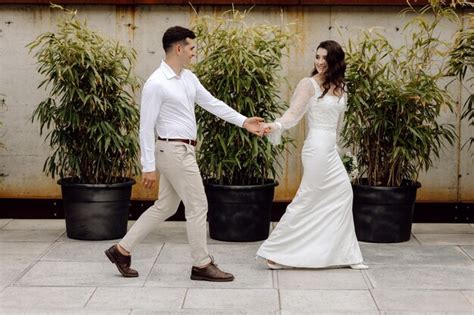 Una Novia Y Un Novio Caminan De La Mano Frente A Las Plantas De Bamb