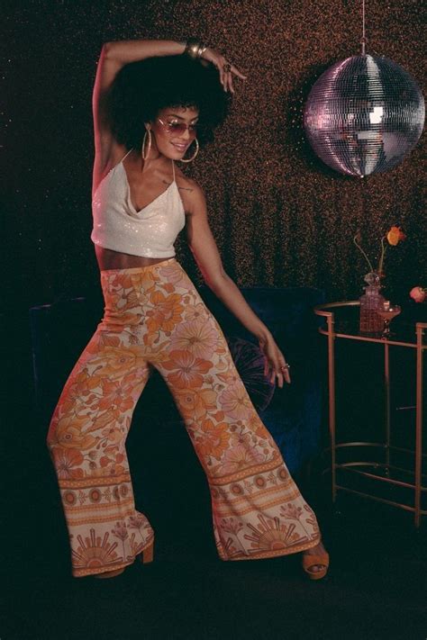 A Woman In Wide Legged Pants Is Dancing With Her Hands Behind Her Head