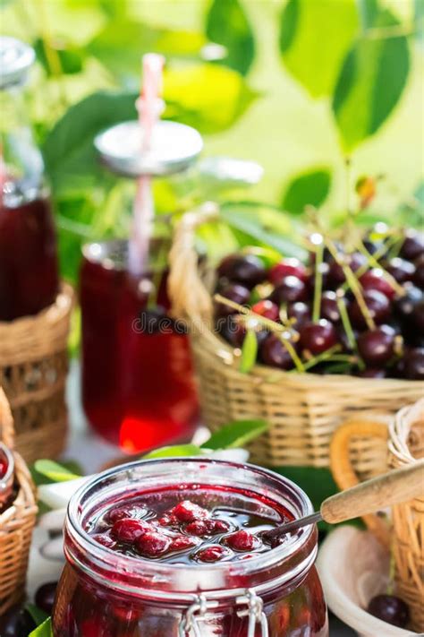 Cooked Homemade Cherry Jam In Glass Jar On White Wooden Table Outdoors