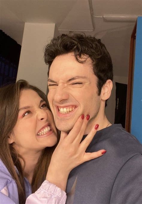 A Man And Woman Smile As They Pose For The Camera With Their Hands