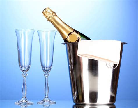 Premium Photo Champagne Bottle In Bucket With Ice And Glasses On Blue