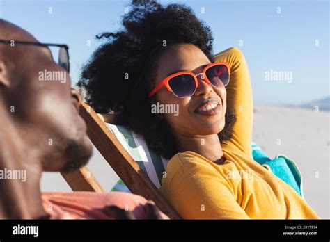 Happy African American Couple In Sunglasses Sitting In Deckchairs