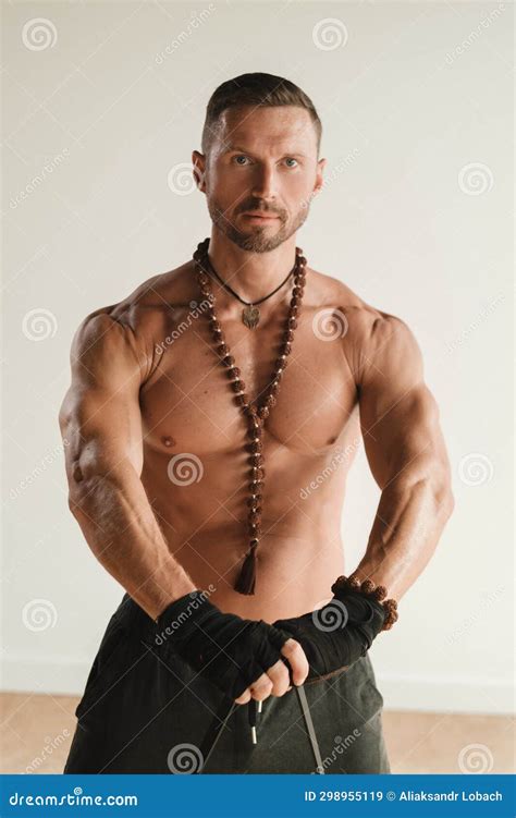 A Man With A Naked Torso Is Engaged In Strength Fitness Using A Rubber