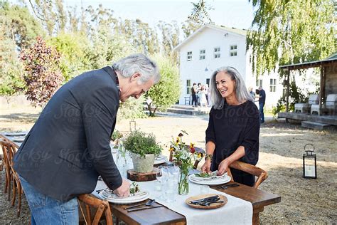 Senior Couple Setting The Table For A Farm To Table Dinner Party At