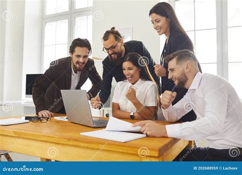 Team Of Excited Colleagues Looking At Laptop Screen Celebrating