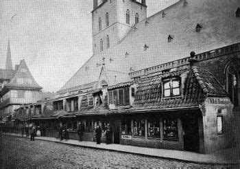 An Old Black And White Photo Of People Walking Down The Street In Front