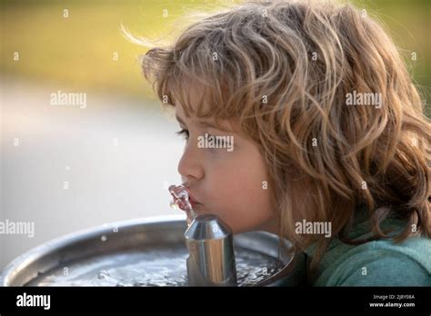 Close up portrait of kid boy drinking water from outdoor water fountain ...
