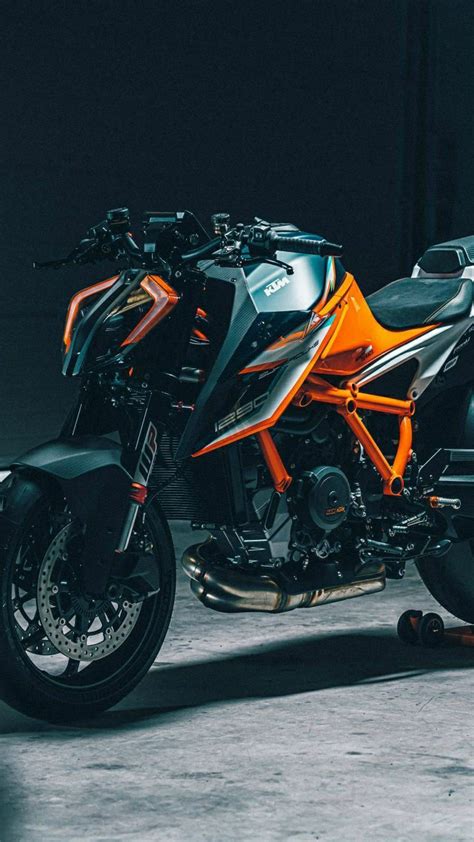 An Orange And Black Motorcycle Is Parked In A Garage With Its Lights On