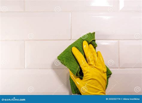 Hand In A Yellow Rubber Glove Wiping The Ceramic Tile Surface With A