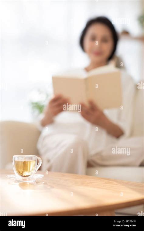 Mature Woman Reading Book On Sofa Stock Photo Alamy