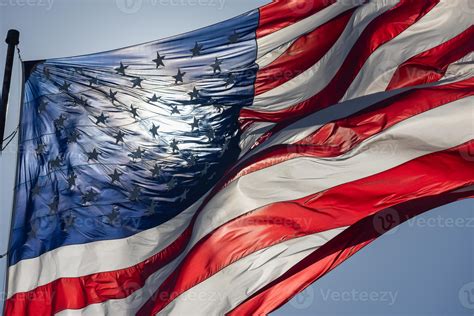 Backlit American Flag Waving In Wind Against A Deep Blue Sky