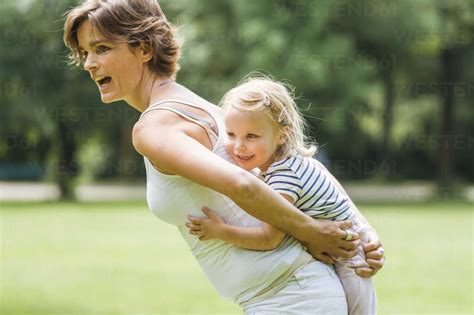 Mutter Tr Gt Ihre Kleine Tochter Huckepack In Einem Park Lizenzfreies