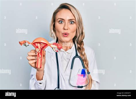 Belle jeune femme blonde tenant le modèle anatomique de l organe génital femelle effrayée et