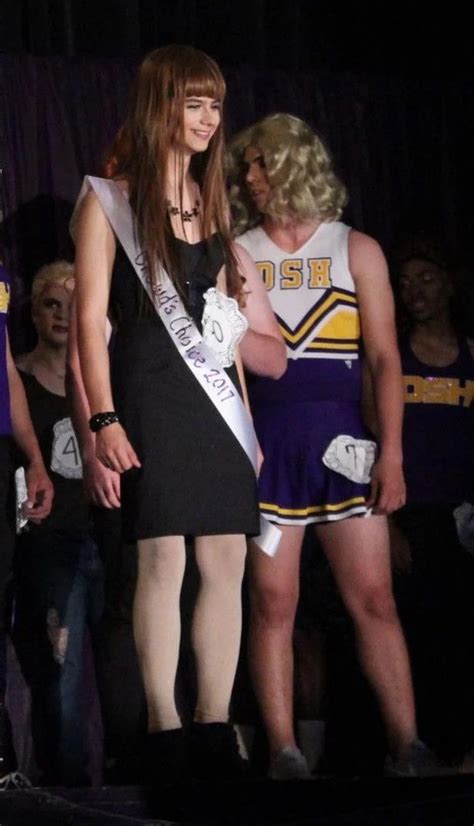 A Woman Standing On Top Of A Stage Next To Another Woman In A Black Dress