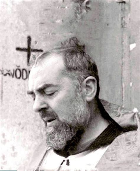 A Black And White Photo Of A Man With A Cross On The Wall Behind Him