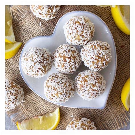 A Heart Shaped Plate Filled With Lemons And Coconut Covered Donuts Next