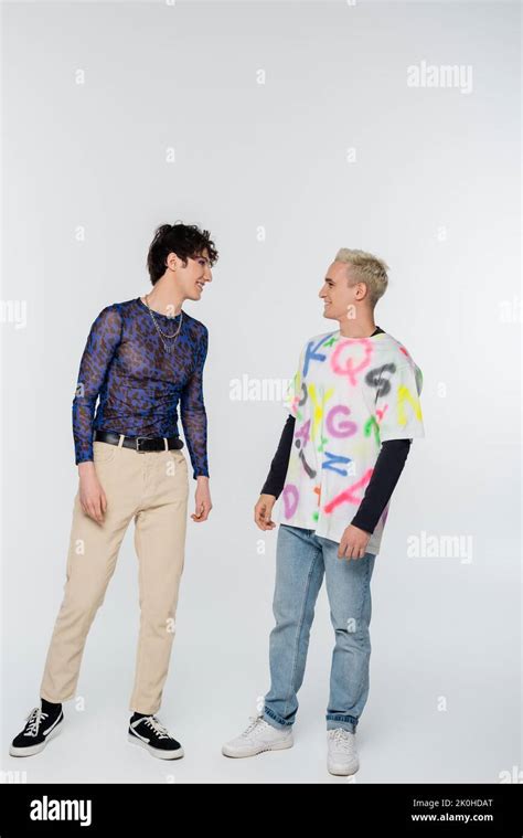 Trendy Gay Man And Nonbinary Person Smiling At Each Other On Grey