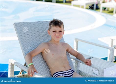 Jeune Garçon Dans Un Maillot De Bain Sur Une étagère Par La Piscine