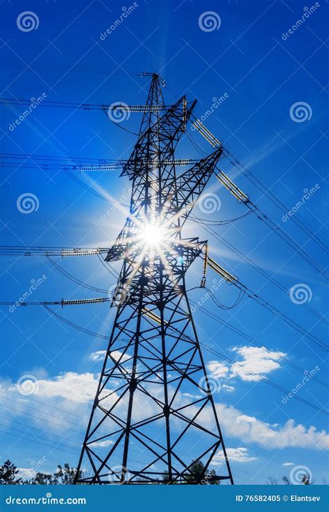 High Voltage Electricity Pylons Against Blue Sky And Sun Rays Stock