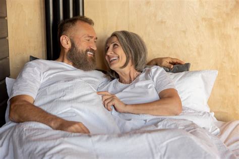 Pareja Madura Que Se Queda En La Cama Y Se Ve Feliz Imagen De Archivo