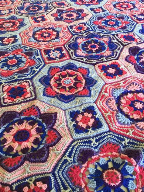 A Crocheted Blanket Is Laying On Top Of A Bed With Red White And Blue