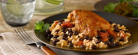 A Plate With Rice Beans And Chicken On It Next To A Glass Of Water