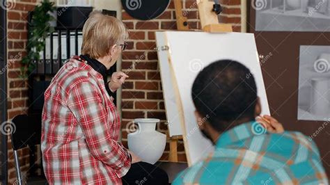 Portrait Of Senior Artist Teaching Drawing Technique At Workshop Stock