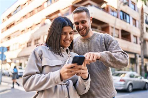 Pareja De Hombres Y Mujeres Sonriendo Confiados Usando Smartphone En La