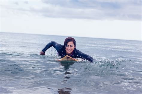 Sonriente Mujer Nadando Sobre La Tabla De Surf En El Agua Foto Premium