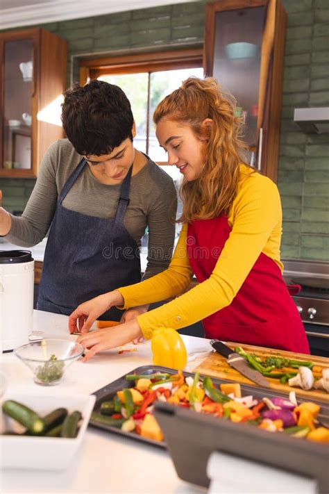 Happy Biracial Lesbian Couple With Tablet Cooking Vegetables In Kitchen Copy Space Stock Image