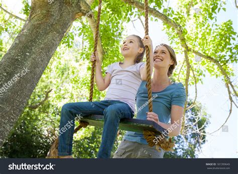 Low Angle View Of A Happy Mother Swinging Daughter At The Park Stock