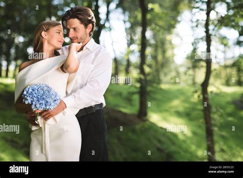 Affectionate Just Married Couple Embracing Standing Together In Forest