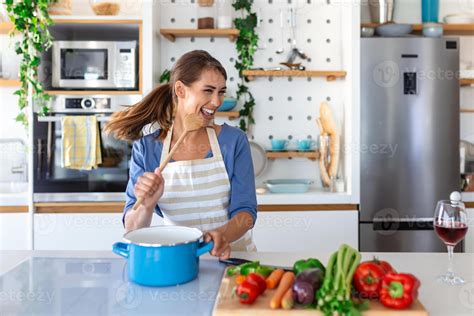 Excited Woman Singing And Dancing In Modern Kitchen At Home Happy