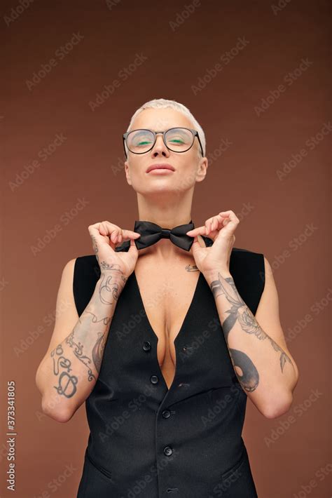 Elegant Female In Black Waistcoat Covering Her Nude Body Tying Bowtie On Neck Stock Photo