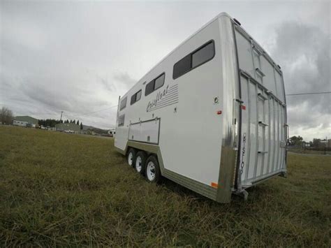 A Horse Trailer Parked In The Middle Of A Field With No People Around