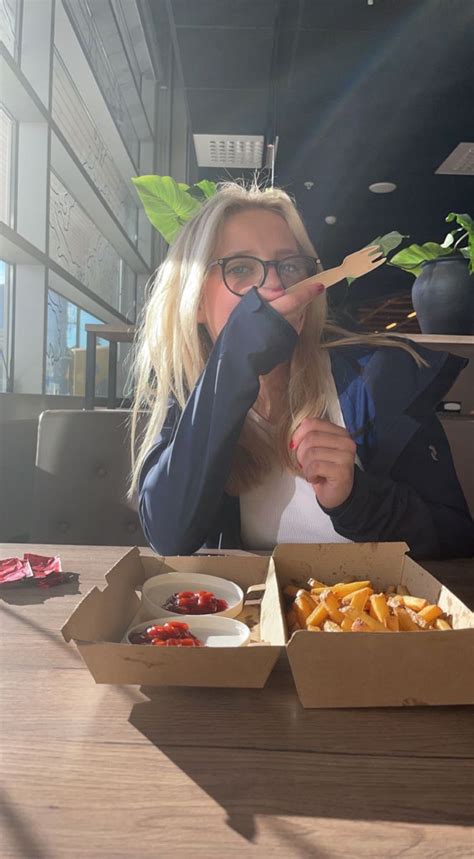 A Woman Sitting At A Table Eating Food With Chopsticks In Front Of Her