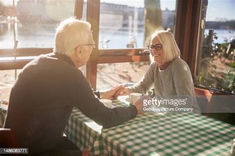 Smiling Couple Holding Hands And Drinking Coffee In Cafe Photos And