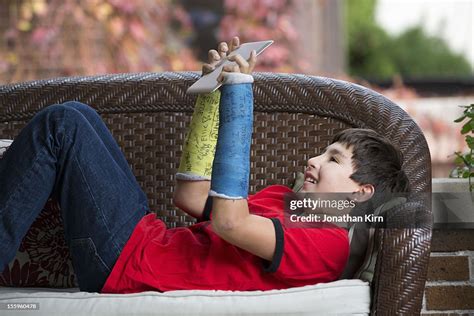 Boy With Two Broken Arms Enjoys Time On A Tablet High Res Stock Photo