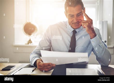 Smiling Mature Businessman Wearing A Shirt And Tie Sitting Alone At His