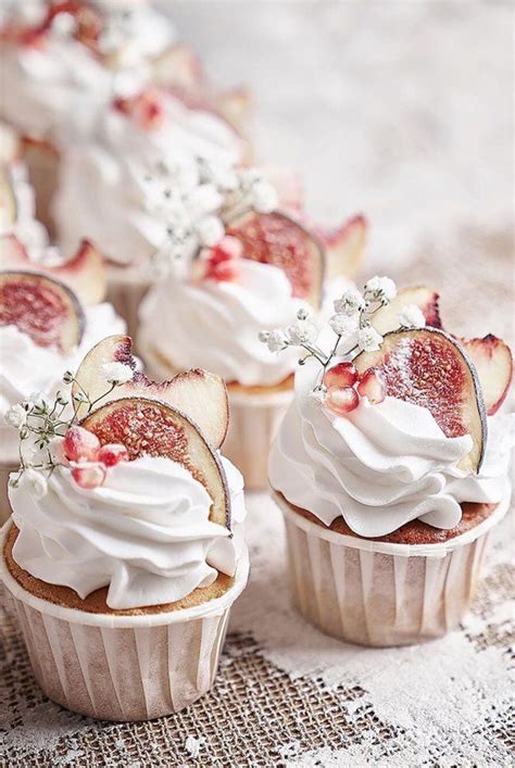 Some Cupcakes With White Frosting And Fruit On Top Are Sitting On A Table