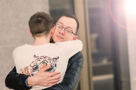 Joven pareja gay sonriendo feliz y abrazándose en la ciudad Foto Premium