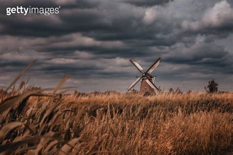 Majestic Windmill Atop A Grassy Field Under A Stormy Sky In Kinderdijk